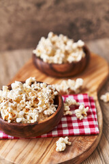 Obraz na płótnie Canvas Bowls of salty popcorns on a wooden surface