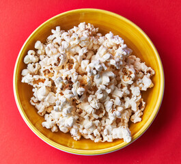  Bowl of salty popcorns on a red background