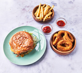  Plate of classical hamburger with chips potatoes and onion rings on a marble surface