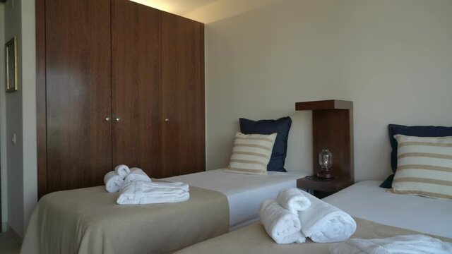 Video filming of the hotel modern bedroom room with bed and pillows. And white towels and a robe for hostel visitors.