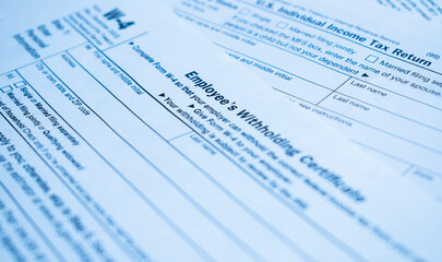 A closeup of the Form W-4, Employee's withholding certificate, and a fountain pen on a wooden surface