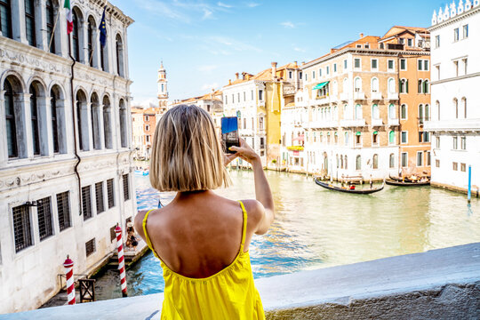 Blonde woman, traveler tourist make photos by mobile phone in venice Italy. Summer day.