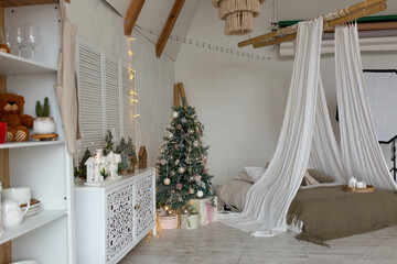 Bright large bedroom. New Year's interior, New Year's tree by the bed is decorated with balls. Christmas mood. bed with pillows