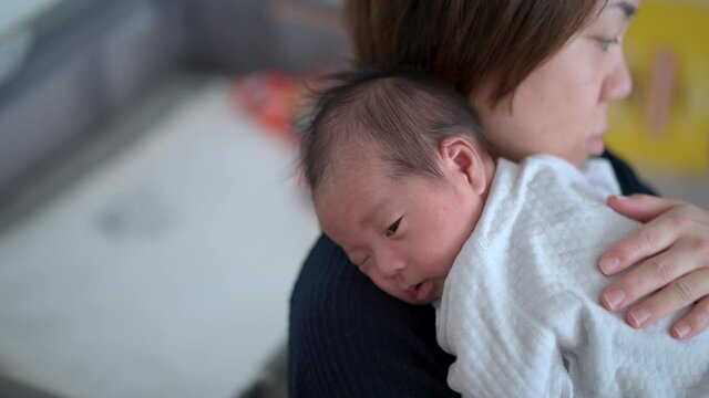 asian mother burping her newborn baby