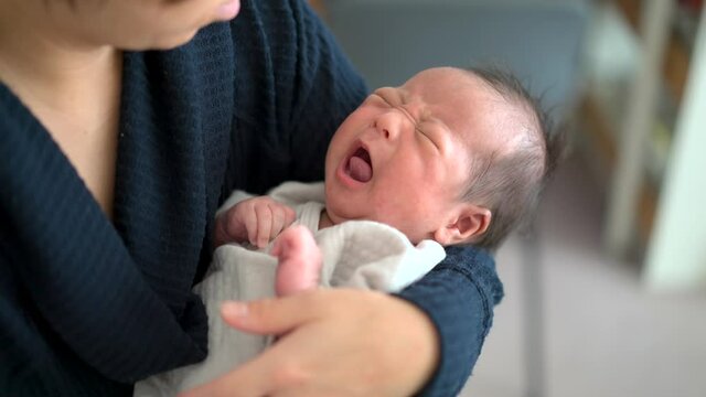 asian mother holding her crying newborn baby