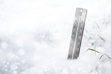 Thermometer in the snow during a cold snap in winter, concept for weather phenomena, climate change and rising heating costs, copy space, selected focus