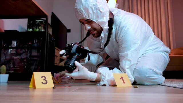 Forensic scientist  in protective suite collecting evidence and taking photos at crime scene.  Looking For Evidence And Clues and Photographing . Police investigation.