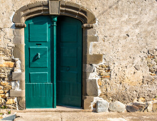 Dark green double door of an old castle in southern France