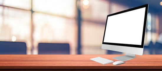 Computer desktop with blank screen on wood table in blurry background with house or office modern ,nature orange bokeh and sunlight in morning.