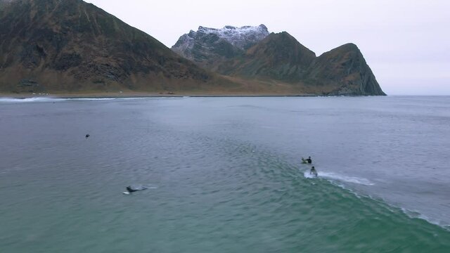 Aerial view of surfers in arctic waters of Lofoten, Norway - tracking, drone shot