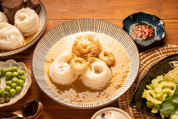Rice noodles or Kkanomjeen namya krati in fish curry sauce with vegetables, Rice vermicelli with minced fishes and coconut milk in red curry.