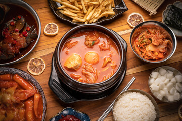Korean traditional Kimchi soup with Tofu mushroom hot pot, Kimchi soup in hot iron pot with rice and Kimchi pickle on wooden table,