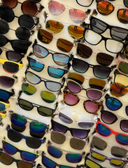 A variety of sunglasses displayed for sale on a foam board outside a shop