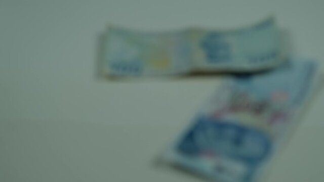 100 lira Turkish coins falling from the air to the white ground