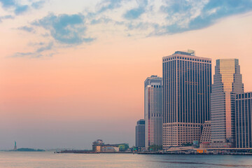 statue of liberty and lower manhattan skyline at dawn