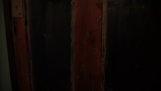 View from inside of an old wooden elevator with glass doors ascending in metal shaft in building with staircase