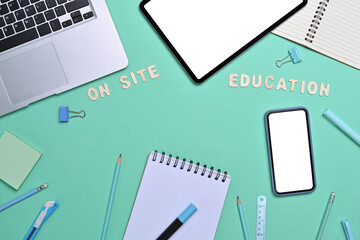 Top view laptop computer, digital tablet, smart phone and stationery on green background.