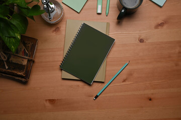 Top view notebooks, pencil, coffee cup and houseplant on wooden table.