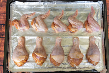 Raw chicken legs and wings on aluminium foil