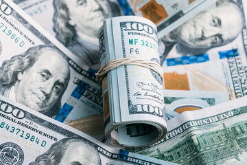 A roll of US one hundred dollar bills laying on a pile of cash from The United States of America