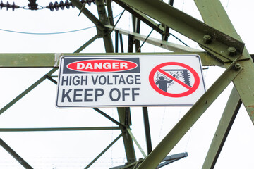 Photograph of a safety sign a large steel electrical transmission tower