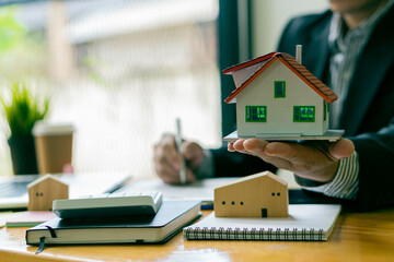 A real estate agent holds a small home and delivers it to the customer after the contract is complete in agreeing to buy a home and lease the concept.