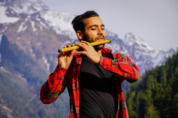 Indian man playing Indian flute in mountains