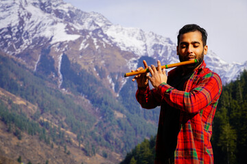 bansuri indian instrument Young boy playing bansuri Indian flute in mountains - obrazy, fototapety, plakaty