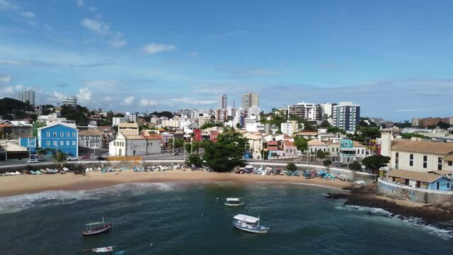 Drone Panorama of Tropical City Coastline with boats, cars passing by and a lot of Buildings in background. Aerial view Red River Beach in Salvador of Carnival, state of Bahia Brazil.