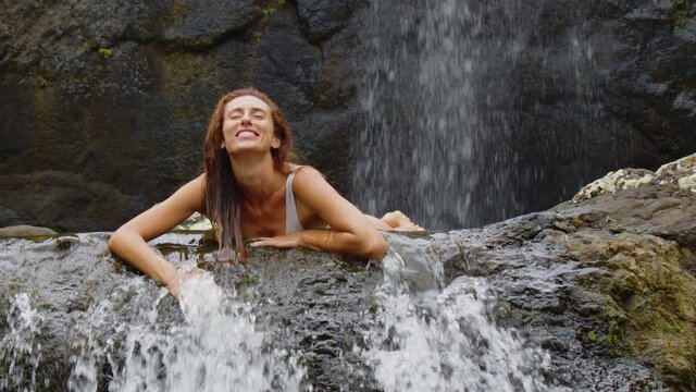 Woman in the water of a waterfall in the mountains. Female hands in fresh clean source water, close up, slow motion