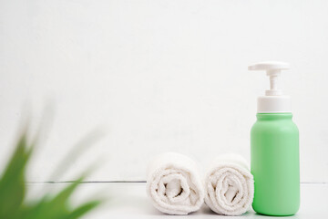 Cosmetic bottles and white towel on table empty space background.Shower items set.Spa objects.Face and body care products.Bathroom tubes.