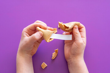 Fortune cookies in the hands of a child on purple background.