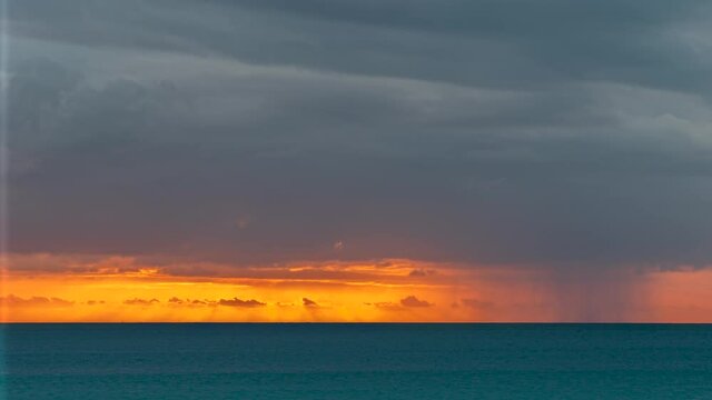 Dark rainclouds move above ocean during tropical sunset at Kuto Bay. Timelapse.