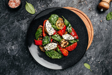 Grilled vegetables with rspinach leaves and feta cheese on a dark background. Restaurant menu, dieting, cookbook recipe top view