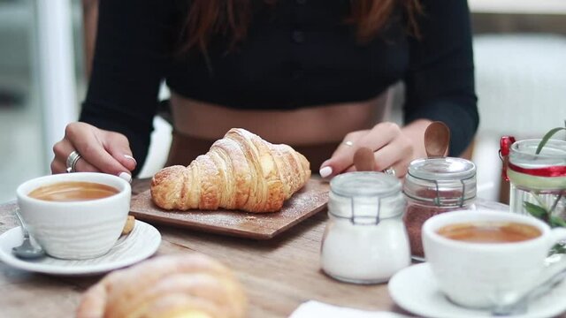 woman having breakfast. croissant and coffee with a sporty girl in the background