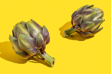 Fresh organic artichoke on yellow background.