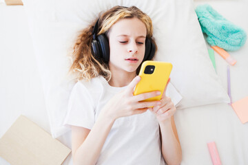 Obraz na płótnie Canvas the girl is a sad child with headphones and a phone