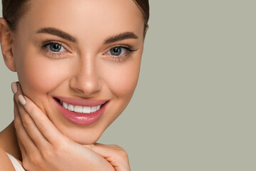 Beautiful skin face woman natural make up healthy skin touching her face. Color background. Green