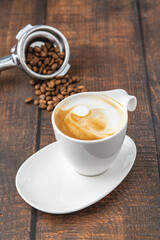 Relaxing latte coffee in white porcelain cup on wooden table