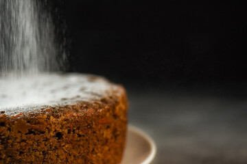 Carrot cake being sprinkled with sugar powder