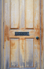A black and white image of a vintage door with a mail slip in the center