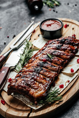Pork ribs grilled with BBQ sauce. Tasty snack on wooden board. Food recipe background. Close up