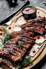 Close up of spicy grilled spare ribs with BBQ sauce on dark background, Hot grilled spare ribs on cutting board
