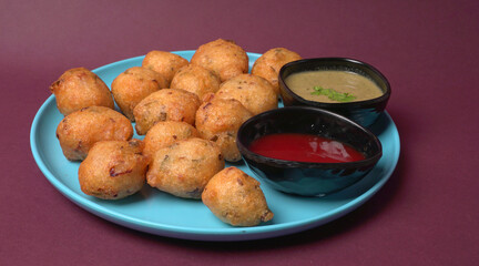 Delicious Indian snacks Punugulu served in a plate with Tomato and green Chutney
