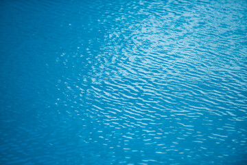 Water background, ripple waves. Blue swiming pool pattern. Sea surface. Water in swimming pool with sun reflection. Banner with copy space.