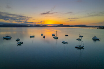 Sunrise waterscape with boats, soft clouds and reflections