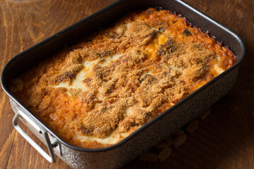 Vegan baked rice in baking dish on wooden background.