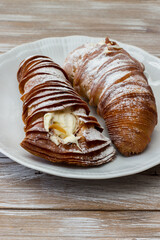 Sweet lobster tails with cream in a white serving plate. Italian pastry. Isolated on wooden...