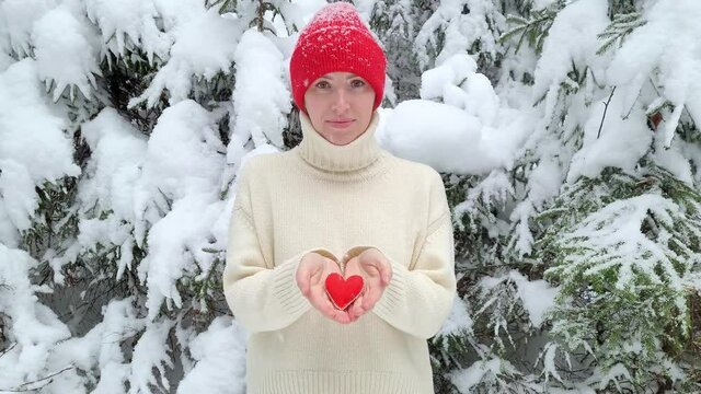 Gioconda's Smile woman take back Red heart, pray. Closing feelings, lonelyness. Felt, winter forest, white ivory sweater. Concept of giving, confessing love Valentine's Day. Revealing feelings, trust.