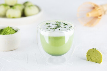 Matcha latte tea in a glass with truffles on the table. Sugar, gluten and lactose free and vegan.